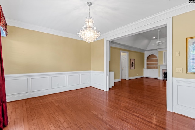 unfurnished room featuring a fireplace, wood finished floors, ornamental molding, and wainscoting