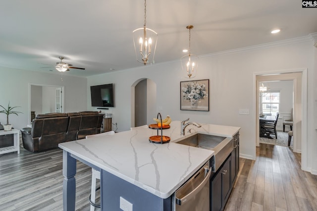 kitchen featuring arched walkways, a sink, stainless steel dishwasher, and light wood-style floors
