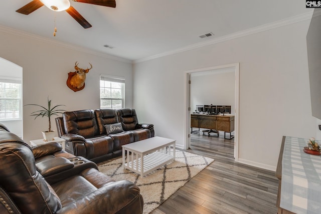 living area with wood finished floors, baseboards, visible vents, ceiling fan, and ornamental molding