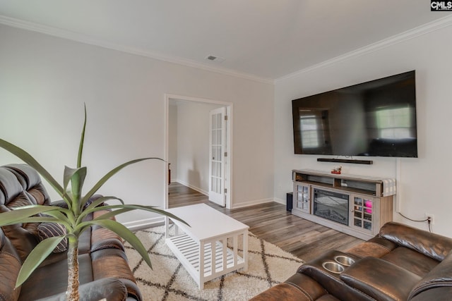 living area featuring visible vents, ornamental molding, baseboards, and wood finished floors