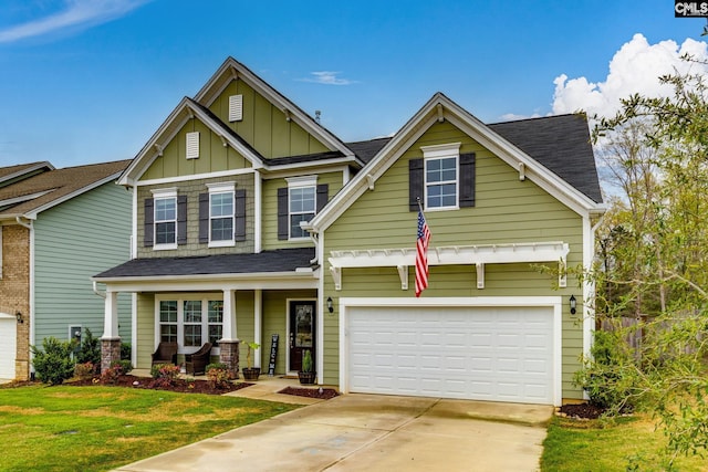 craftsman house with a front yard, concrete driveway, an attached garage, board and batten siding, and a porch