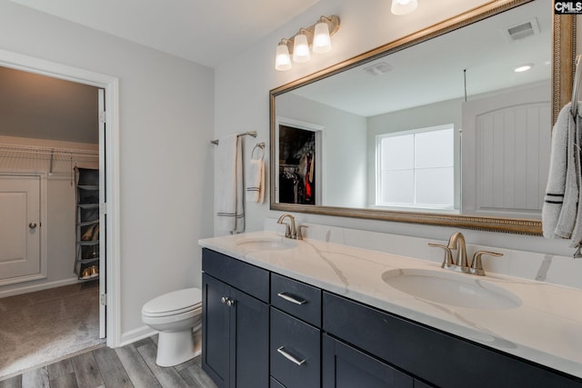 full bathroom with toilet, a sink, wood finished floors, and visible vents