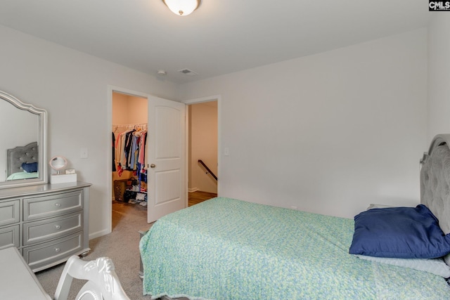 bedroom featuring a spacious closet, light carpet, a closet, and visible vents