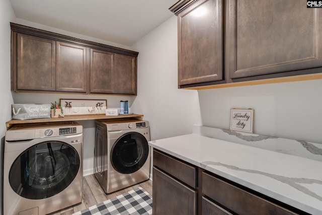 washroom with washing machine and clothes dryer, cabinet space, and light wood-style floors