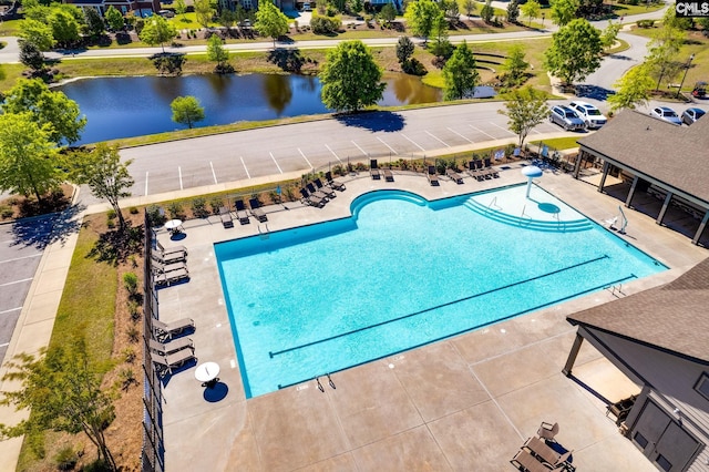 view of swimming pool featuring a water view, fence, and a patio