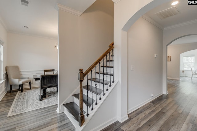 stairway featuring visible vents, crown molding, arched walkways, and wood finished floors