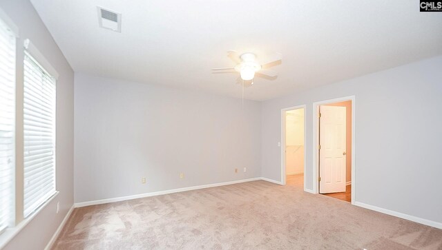 carpeted empty room with a ceiling fan, baseboards, and visible vents