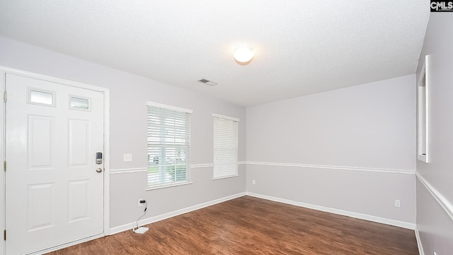 entrance foyer with baseboards, visible vents, dark wood-type flooring, and a textured ceiling