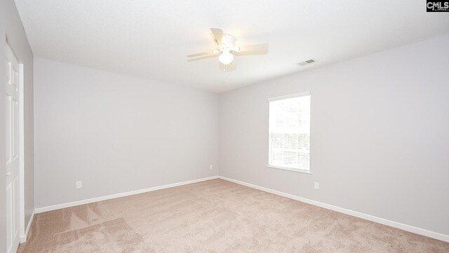 spare room with baseboards, ceiling fan, visible vents, and light colored carpet