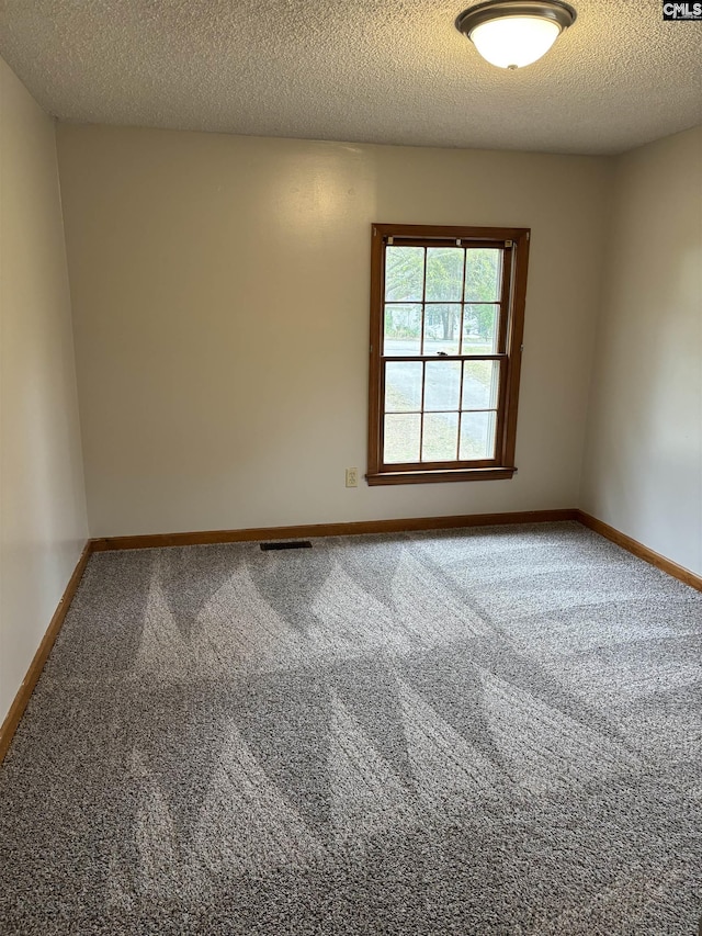 empty room featuring baseboards, carpet floors, a textured ceiling, and visible vents