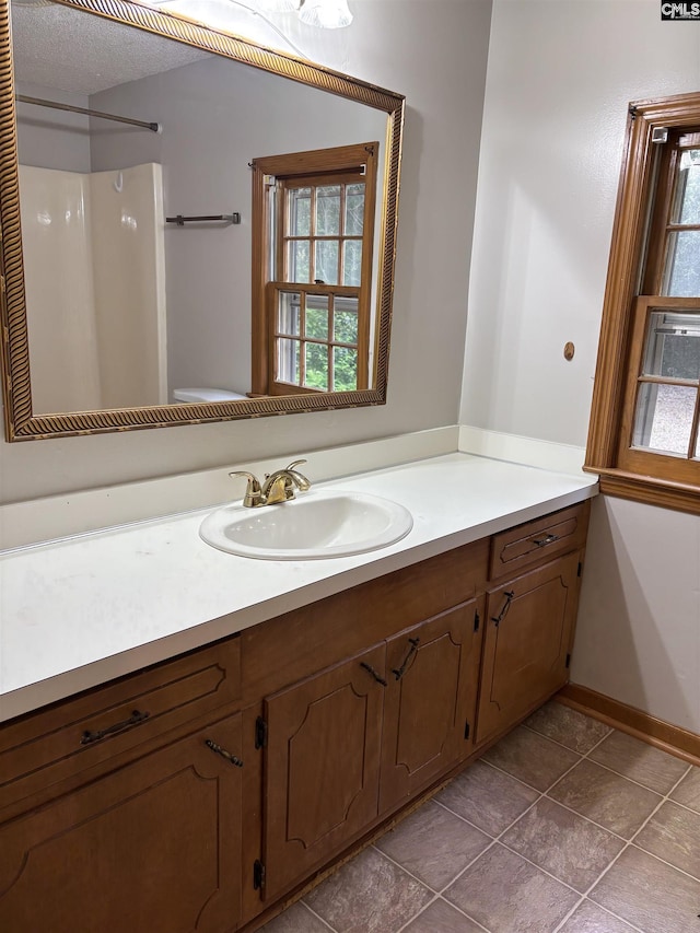 full bath with a shower, vanity, plenty of natural light, and baseboards