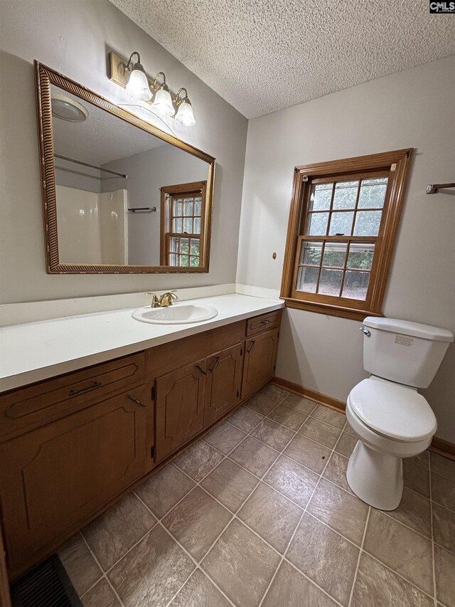 full bath with toilet, vanity, baseboards, and a textured ceiling