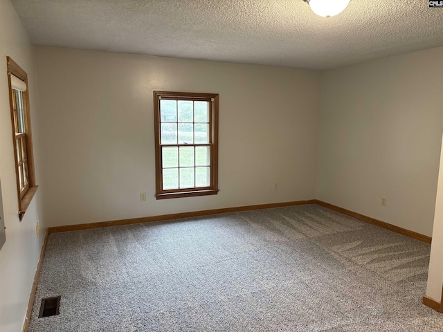 spare room featuring carpet flooring, a textured ceiling, baseboards, and visible vents