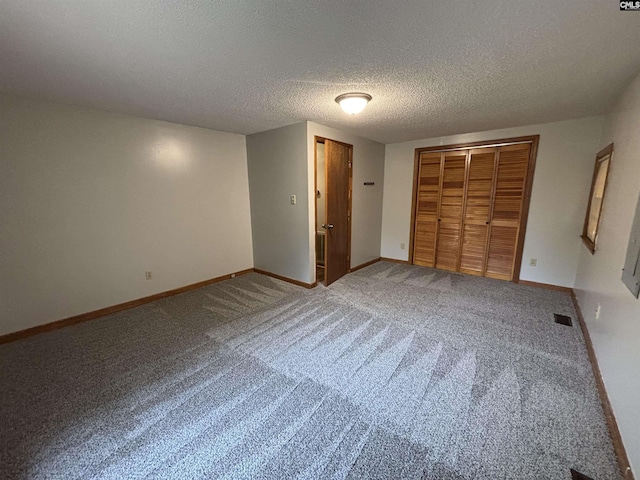 unfurnished bedroom with a closet, carpet flooring, a textured ceiling, visible vents, and baseboards