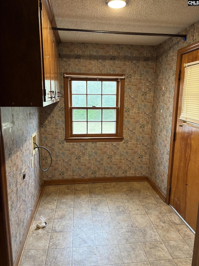 spare room with light tile patterned floors, baseboards, and a textured ceiling