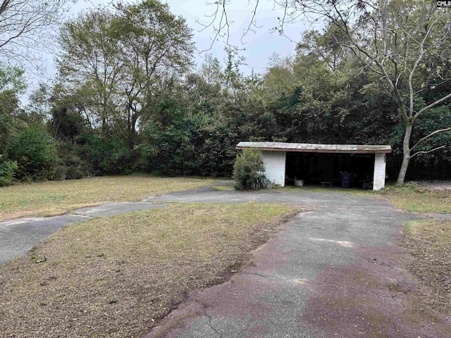view of yard with an outdoor structure, aphalt driveway, and a carport