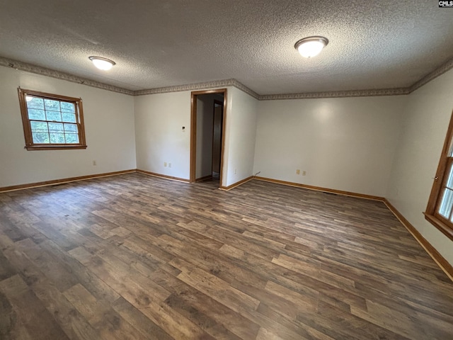 spare room featuring baseboards, crown molding, a textured ceiling, and dark wood-style flooring