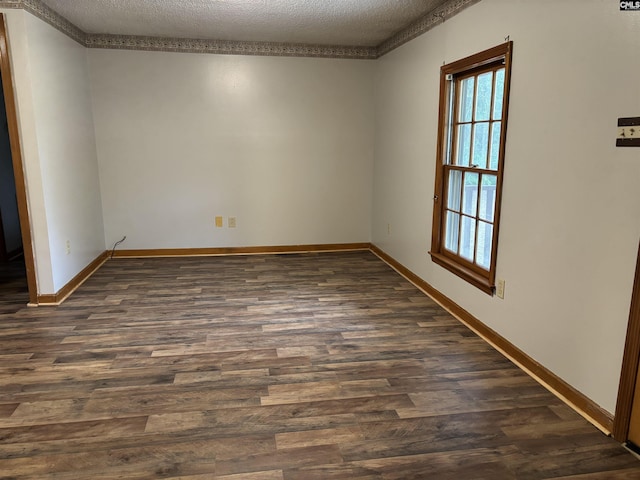 empty room featuring a textured ceiling, dark wood-style floors, and baseboards