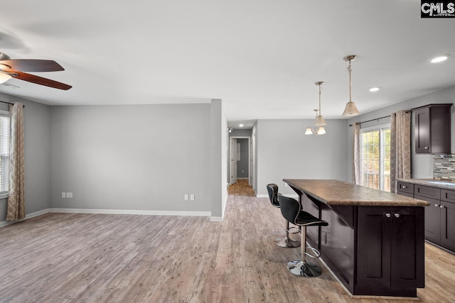 kitchen with a kitchen island, baseboards, light wood finished floors, and ceiling fan