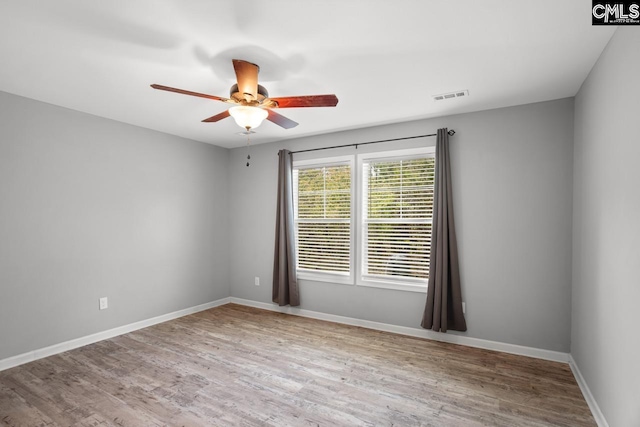empty room featuring baseboards, visible vents, a ceiling fan, and wood finished floors