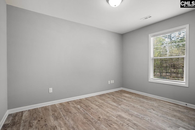 unfurnished room featuring wood finished floors, baseboards, and visible vents