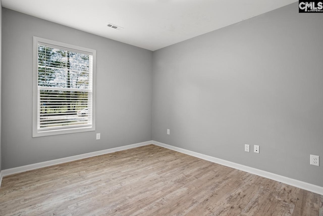 unfurnished room with baseboards, visible vents, and wood finished floors