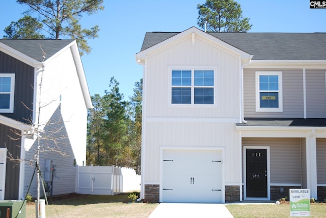 view of front of property with a garage, stone siding, fence, and board and batten siding