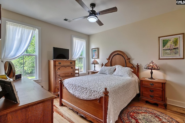bedroom with light wood finished floors, baseboards, visible vents, and ceiling fan
