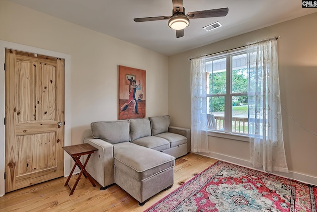 living area with baseboards, visible vents, light wood-style floors, and a ceiling fan