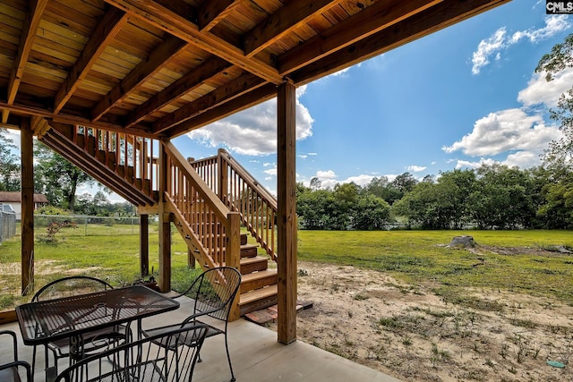 view of patio with fence, outdoor dining area, and stairway