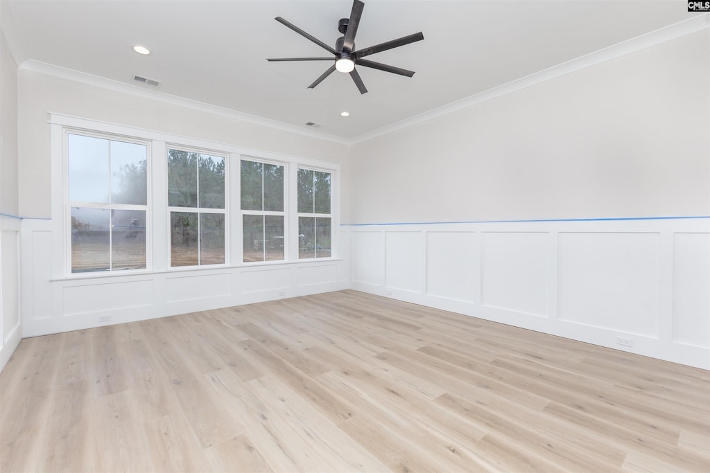 empty room with light wood finished floors, visible vents, ornamental molding, and a ceiling fan