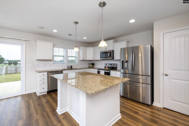 kitchen with white cabinets, a kitchen island, appliances with stainless steel finishes, and dark wood finished floors