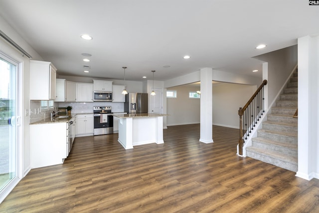 kitchen featuring dark wood finished floors, a sink, appliances with stainless steel finishes, and a kitchen island