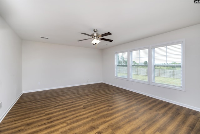 unfurnished room featuring a ceiling fan, dark wood-type flooring, baseboards, and visible vents