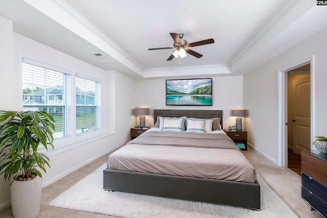 carpeted bedroom with baseboards, visible vents, ornamental molding, and a raised ceiling
