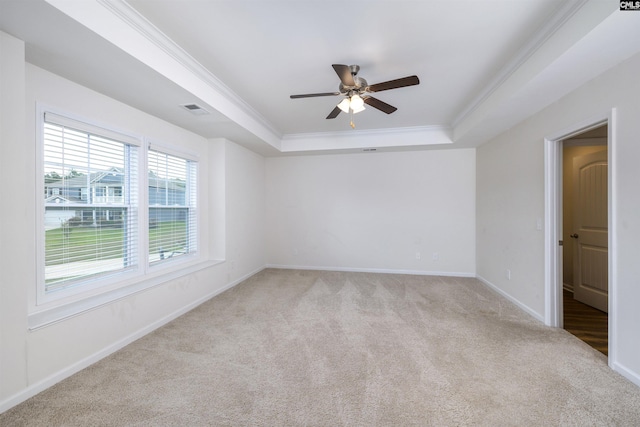 carpeted spare room featuring visible vents, crown molding, baseboards, a ceiling fan, and a tray ceiling