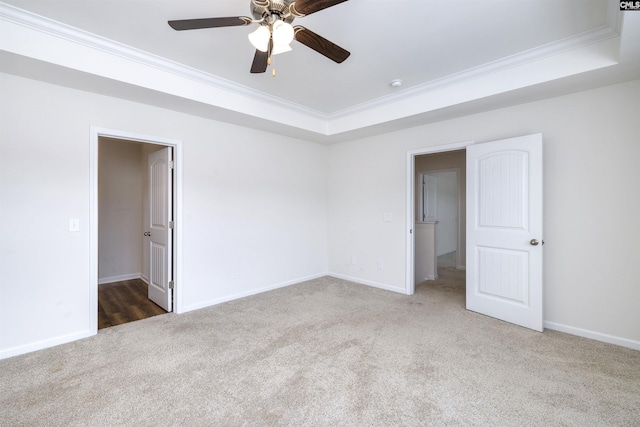 carpeted empty room featuring baseboards, a tray ceiling, crown molding, and ceiling fan