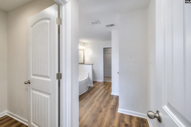 corridor featuring dark wood-style flooring, baseboards, and visible vents