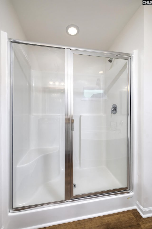 full bathroom featuring wood finished floors and a stall shower