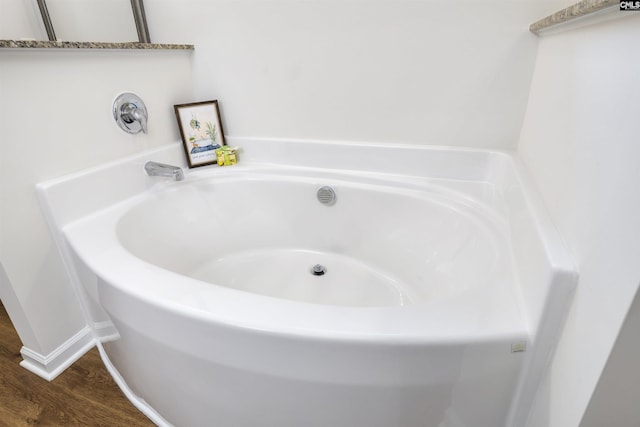 full bathroom with baseboards, wood finished floors, and a bath