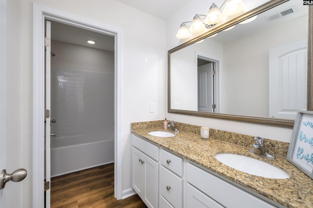 bathroom featuring double vanity, visible vents, wood finished floors, and a sink