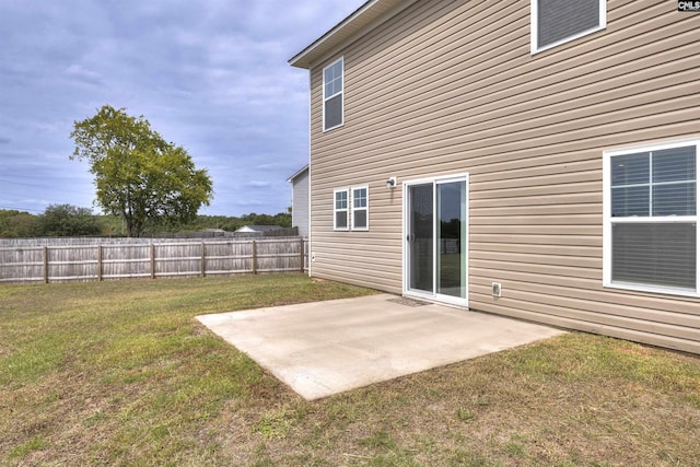 rear view of property featuring a patio, fence, and a lawn