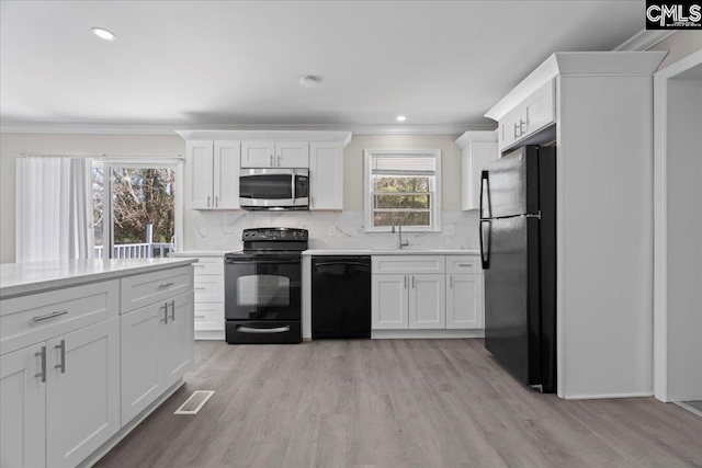 kitchen featuring light wood-type flooring, decorative backsplash, black appliances, and visible vents