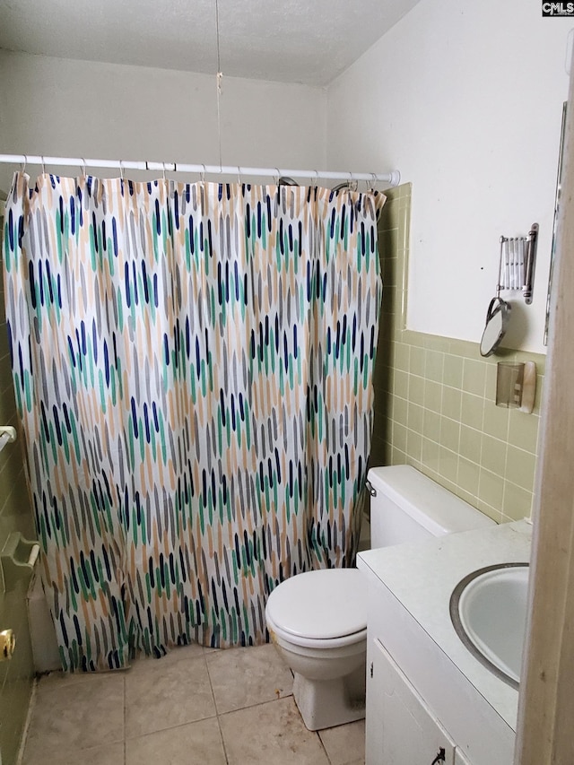 full bathroom featuring shower / bath combination with curtain, toilet, tile walls, vanity, and tile patterned flooring