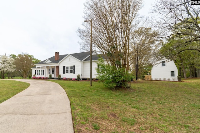 view of front of home with a chimney, concrete driveway, and a front lawn