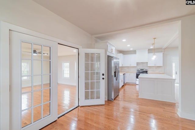 kitchen with light countertops, white cabinetry, tasteful backsplash, appliances with stainless steel finishes, and light wood-style flooring