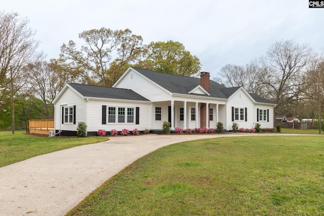 view of front facade with a front yard, concrete driveway, and a chimney
