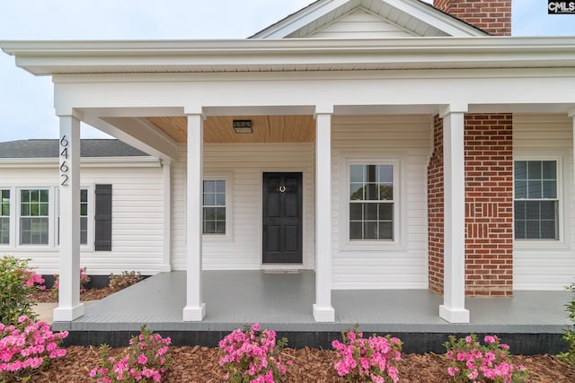 doorway to property with a porch and brick siding