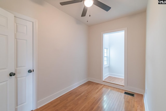 empty room with baseboards, ceiling fan, visible vents, and light wood finished floors