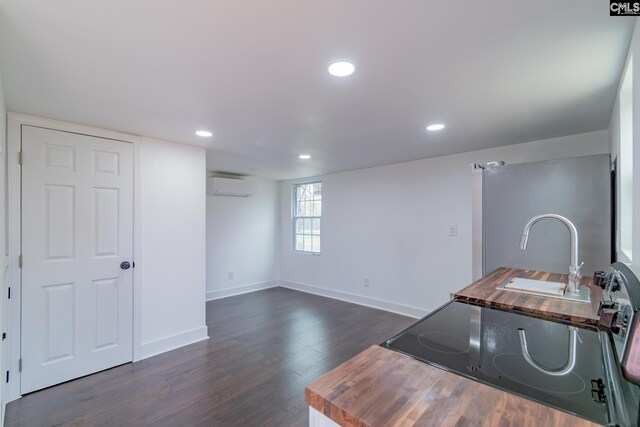 kitchen with recessed lighting, dark wood-type flooring, freestanding refrigerator, a wall unit AC, and electric range